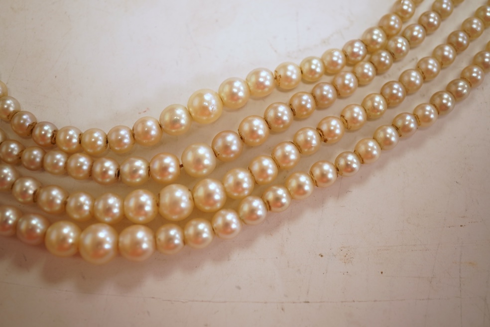Two necklaces, comprising: a three-strand cultured pearl necklace, to a cabochon garnet and diamond clasp, length 34cm; and a paste and gilt metal pendant on a gold chain, chain length 44cm, stamped 14K, gross weight of